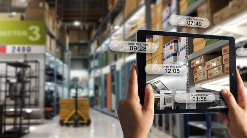 Augmented reality online shopping concept. E-commerce and digital marketing. Hand holding digital tablet smart phone use AR application to check order pick time on storage factory background.