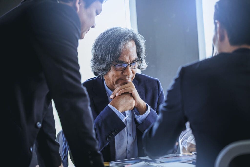 Talking about serious business. Thoughtful business peoples holding hands clasped and looking to business partner while sitting at his working place.