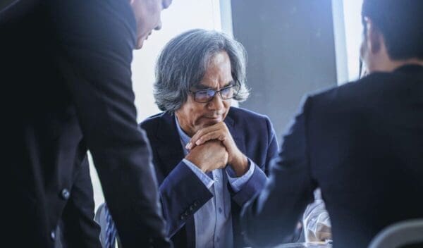 Talking about serious business. Thoughtful business peoples holding hands clasped and looking to business partner while sitting at his working place.