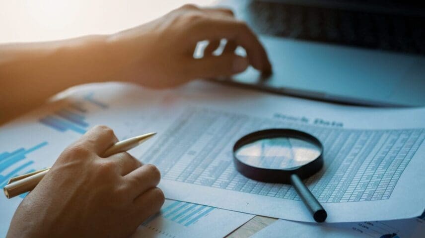 Businessman looking through a magnifying glass to documents. Business assessment and audit. Magnifying glass on a financial report. Close-up Of Businessperson Checking Bills With Magnifying Glass.Concept of search.