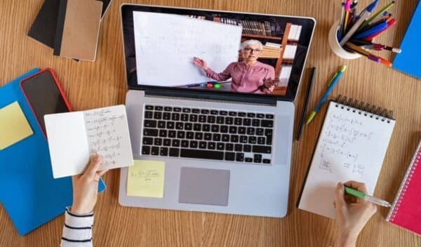 High angle view of video conference with teacher on laptop at home. College student learning maths while watching online webinar, listening audio course. Top view of girl in video call with personal tutor on computer, distance and e-learning education concept.