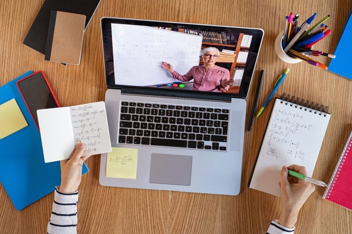 High angle view of video conference with teacher on laptop at home. College student learning maths while watching online webinar, listening audio course. Top view of girl in video call with personal tutor on computer, distance and e-learning education concept.