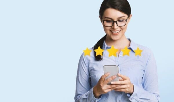 Business App Rating. Happy Millennial Businesswoman Evaluating Mobile Application On Smartphone With Five Stars, Light Studio Background, Panorama