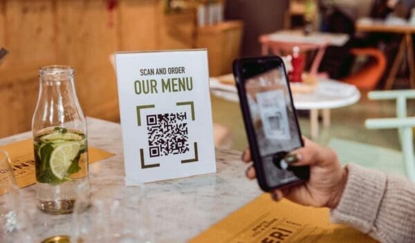 Customer uses QR code on a sign reading "Scan and Order: Our Menu"