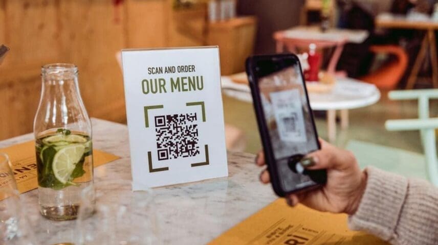 Customer uses QR code on a sign reading "Scan and Order: Our Menu"