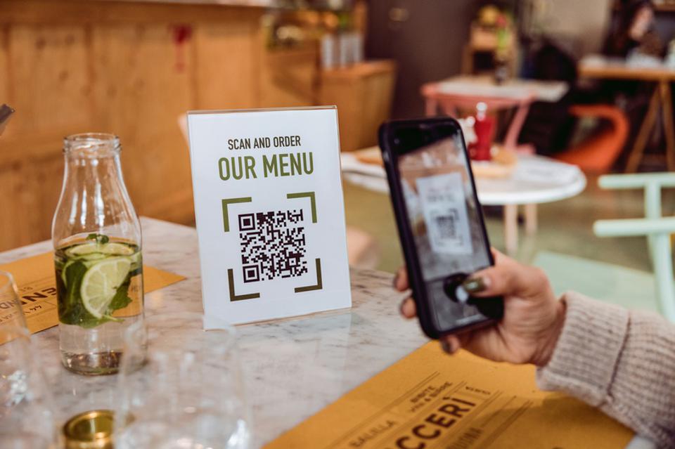 Customer uses QR code on a sign reading "Scan and Order: Our Menu"