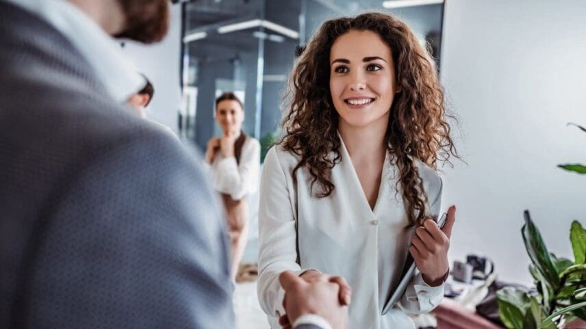 SHot of man and woman shaking hands to visually communicate the HR professional has access to the best HRIS for their organizational needs and makes the right hire.