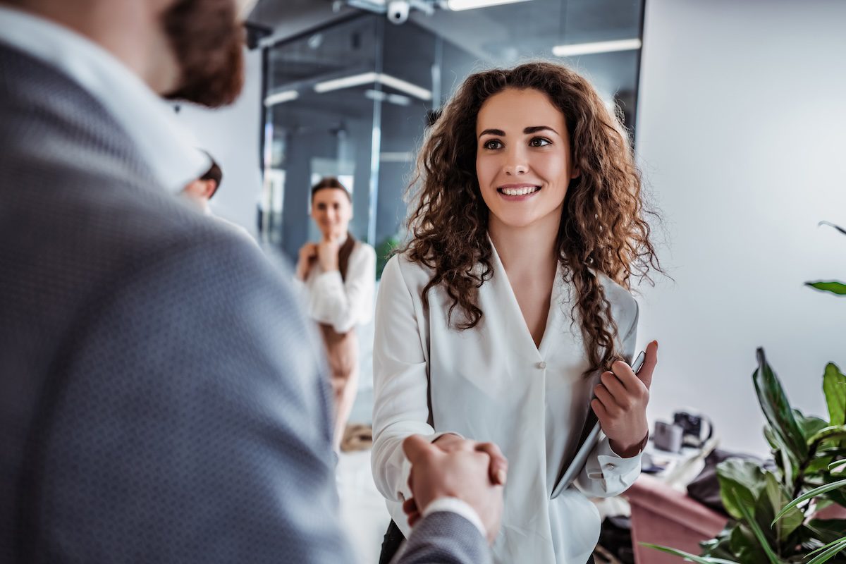 SHot of man and woman shaking hands to visually communicate the HR professional has access to the best HRIS for their organizational needs and makes the right hire.